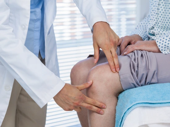 Doctor examining patient's knee to check for knee pain.