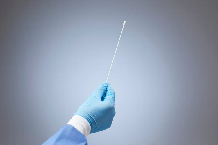 Gloved hand holding sterile swab used for ureaplasma testing during genital infection diagnosis.