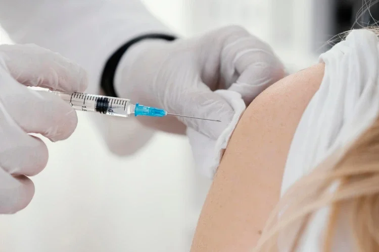 Nurse giving Japanese encephalitis vaccination inject to a female patient 30 days before travelling to a JE endemic region.